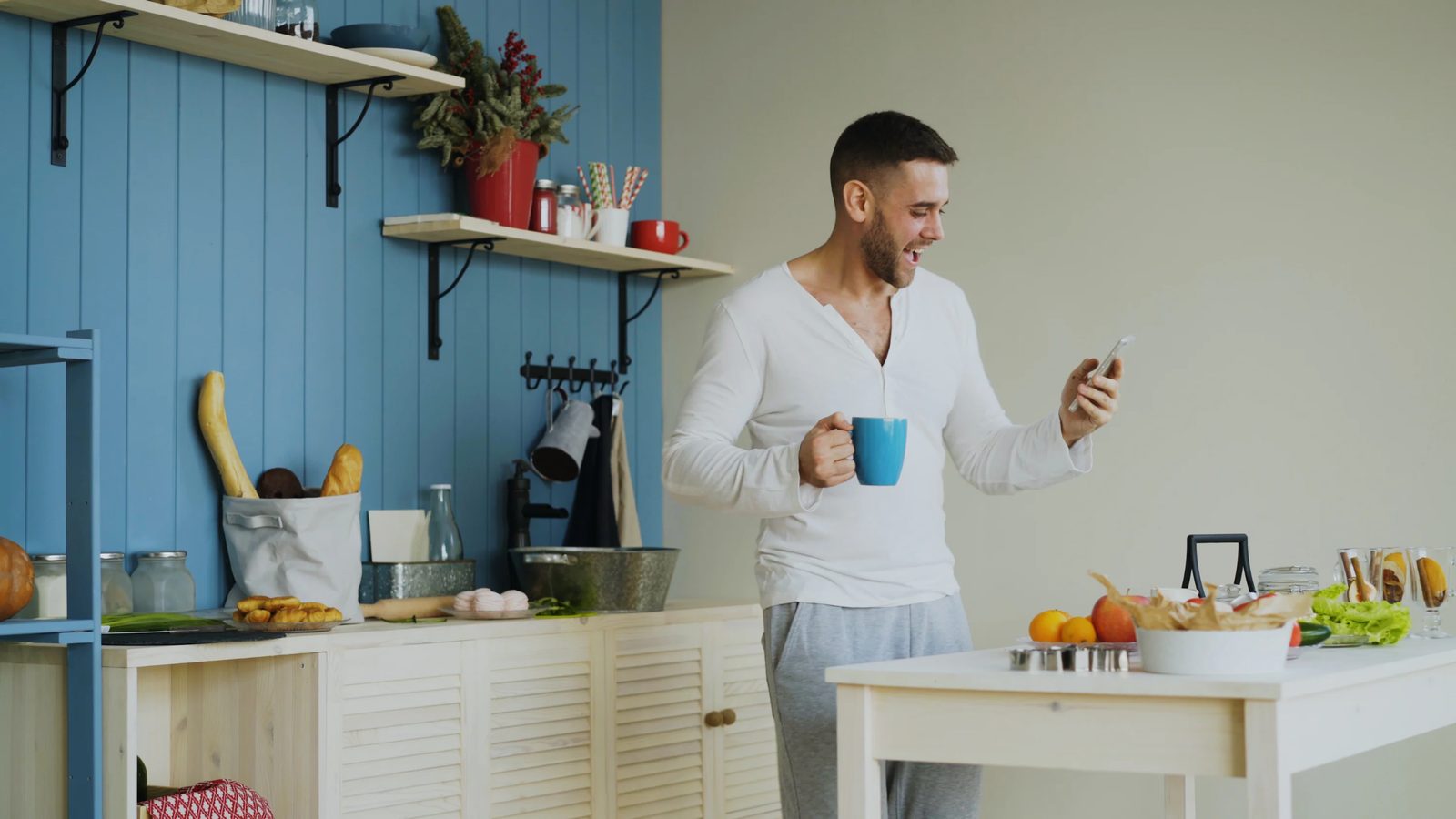 Man holding a coffee cup and looking at his phone in the morning