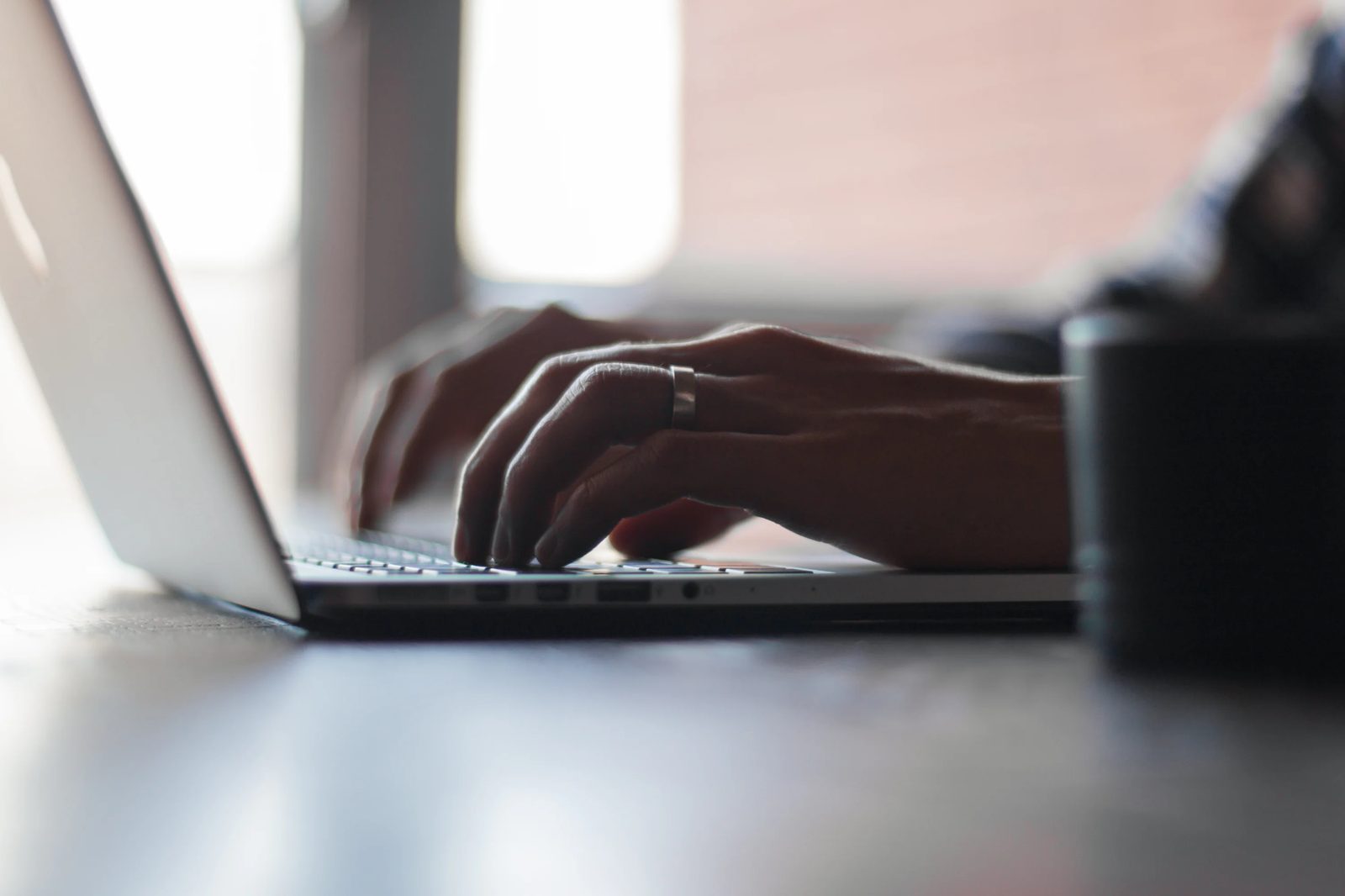 Hands typing quickly on a laptop keyboard
